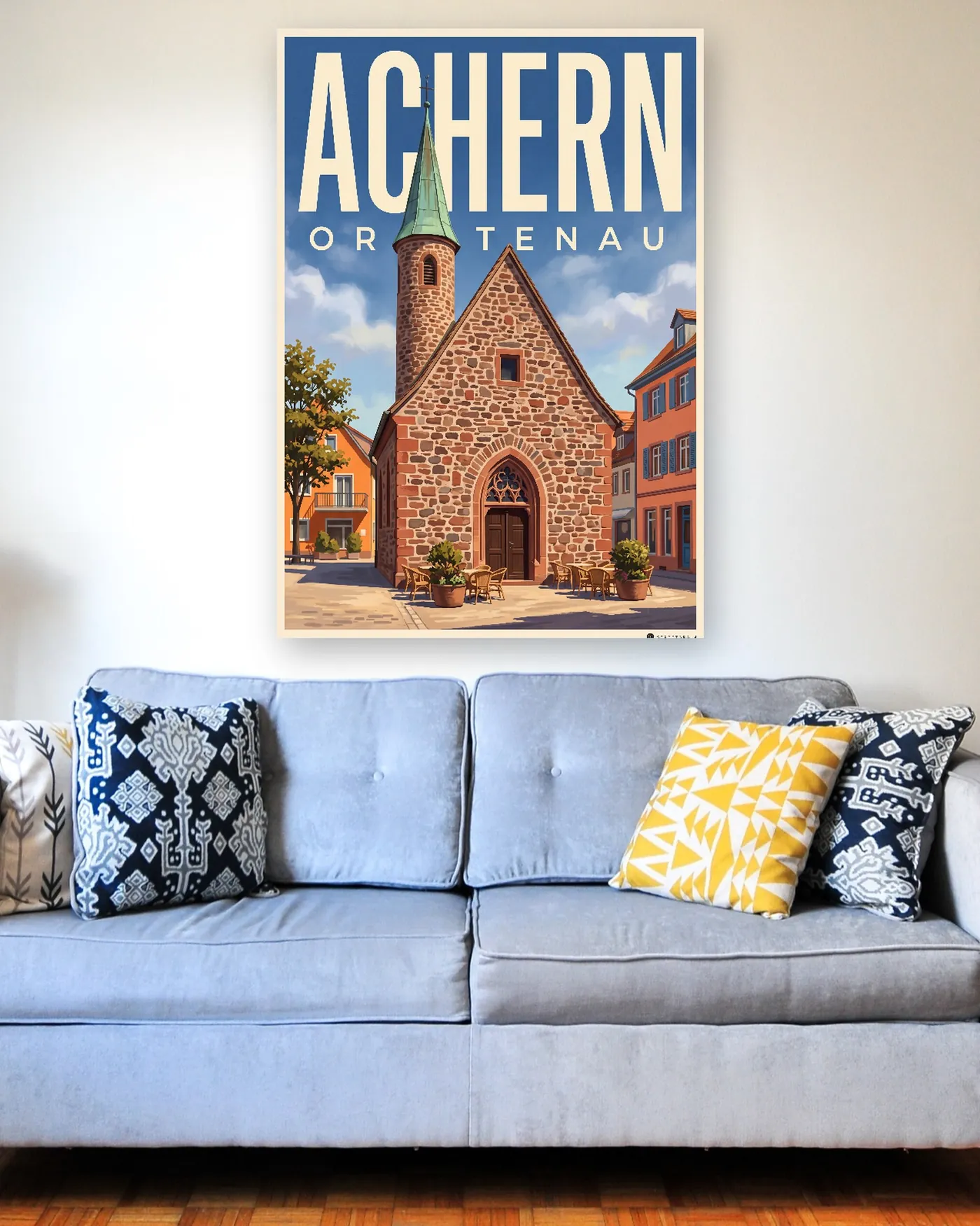 Achern-Poster mit dem Motiv Nikolauskapelle im malerischen Stil über einem hellblauen Sofa