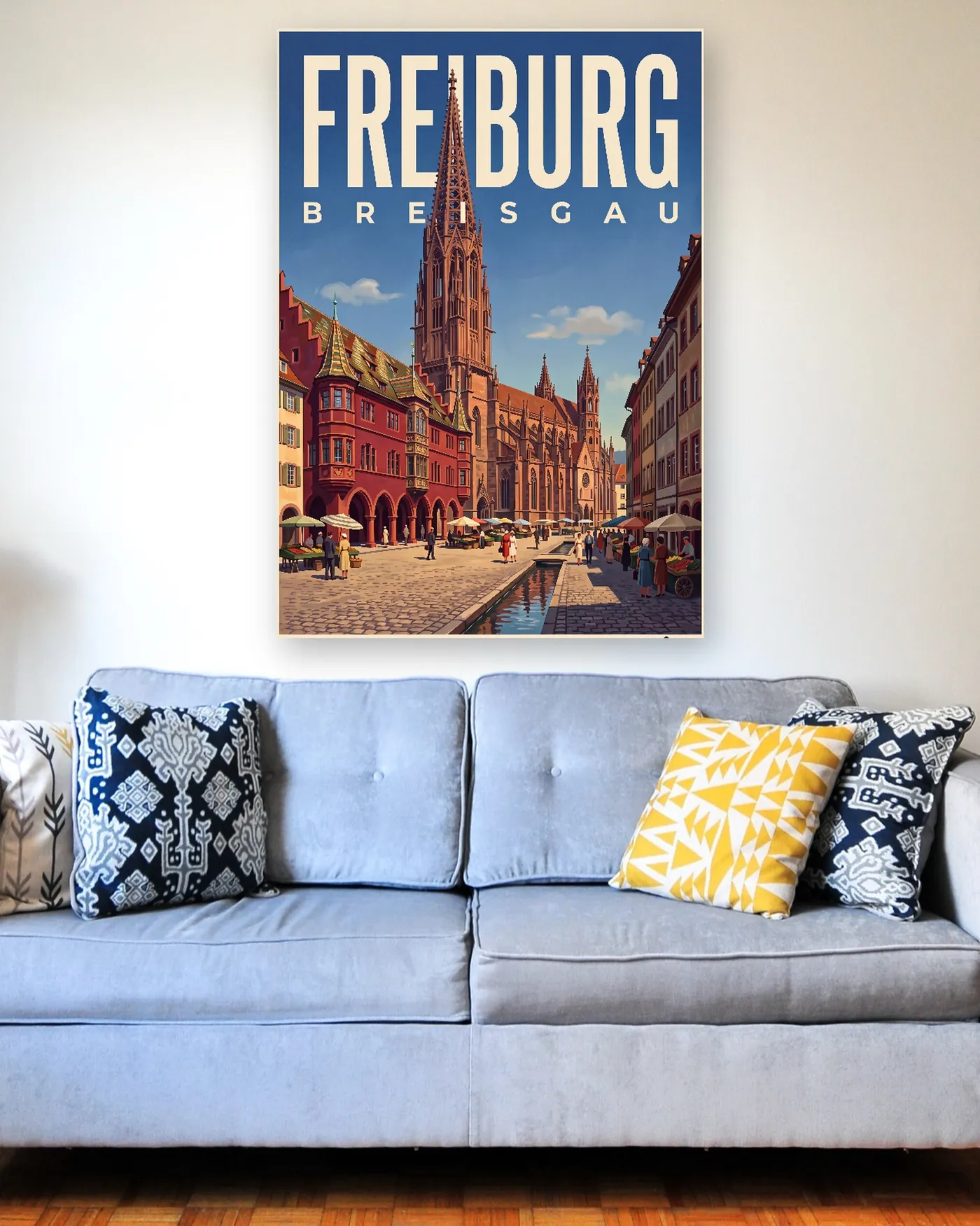 Freiburg-Poster mit dem Motiv Münsterplatz im malerischen Stil über einem hellblauen Sofa